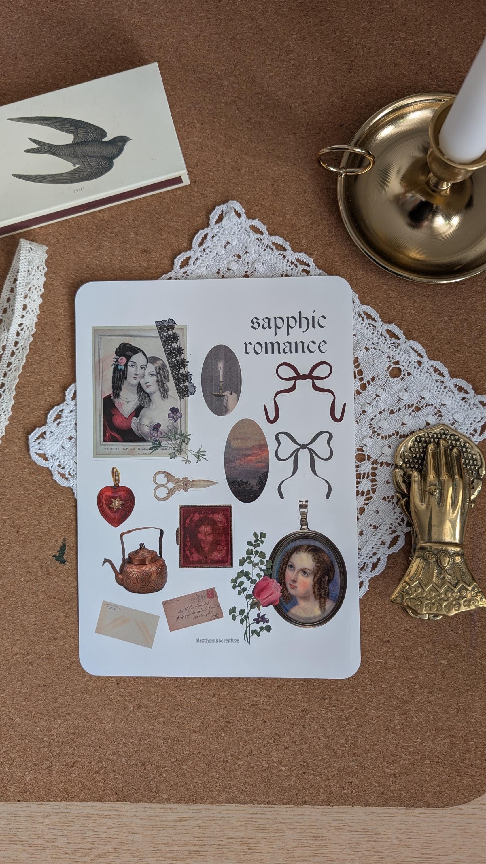 Sticker sheet featuring imagery associated with forbidden, sapphic romance such as diaries, love letters and lockets. The sheet is sitting on a white doily on a wooden surface.
