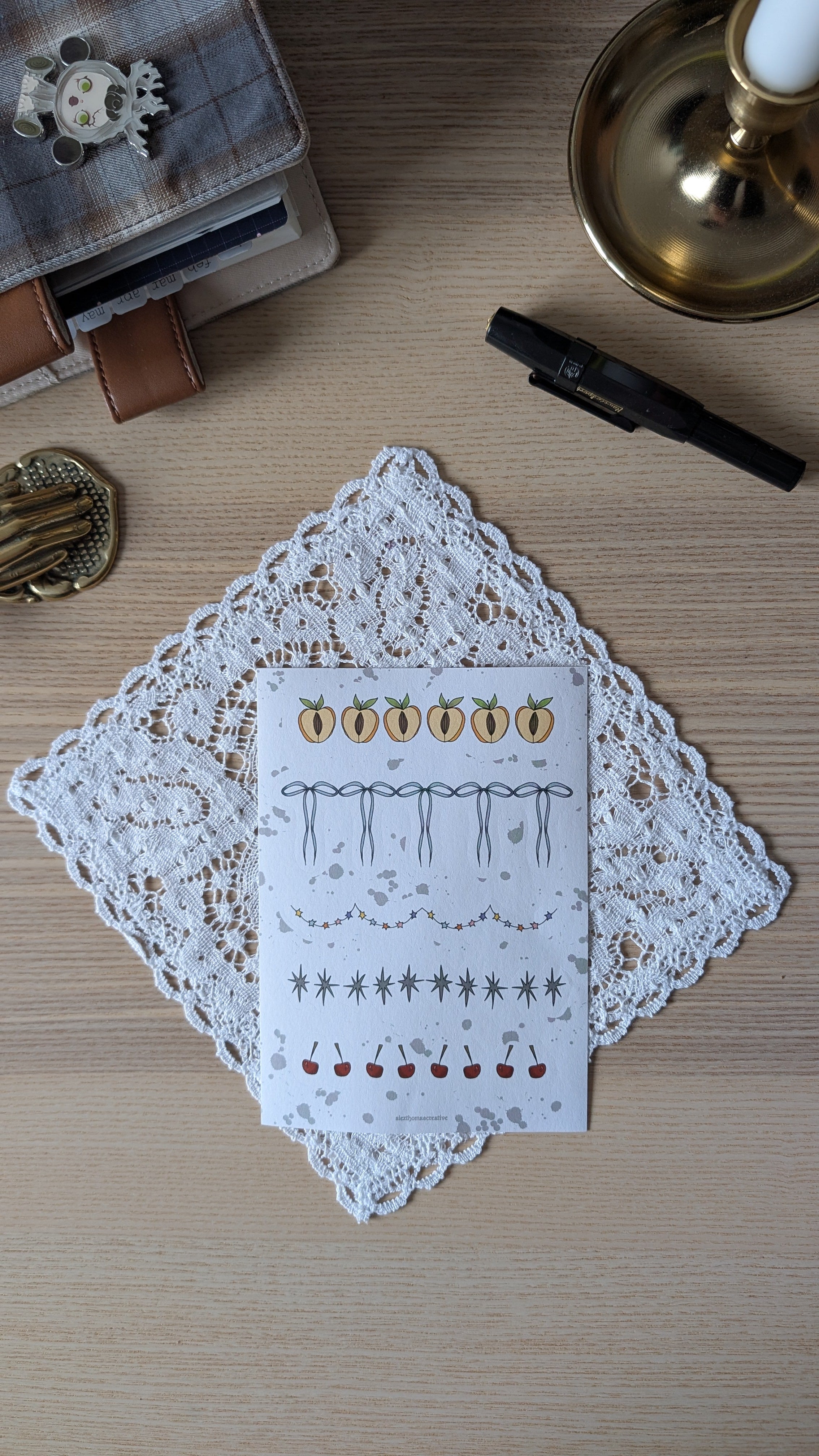 Sticker sheet featuring motifs such as peaches, cherries and garlands. The sheet is sitting on a white doily on a wooden surface.


	
