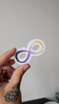 Sticker of an infinity symbol featuring the colours black, purple, white and yellow (the colours of the non binary pride flag).