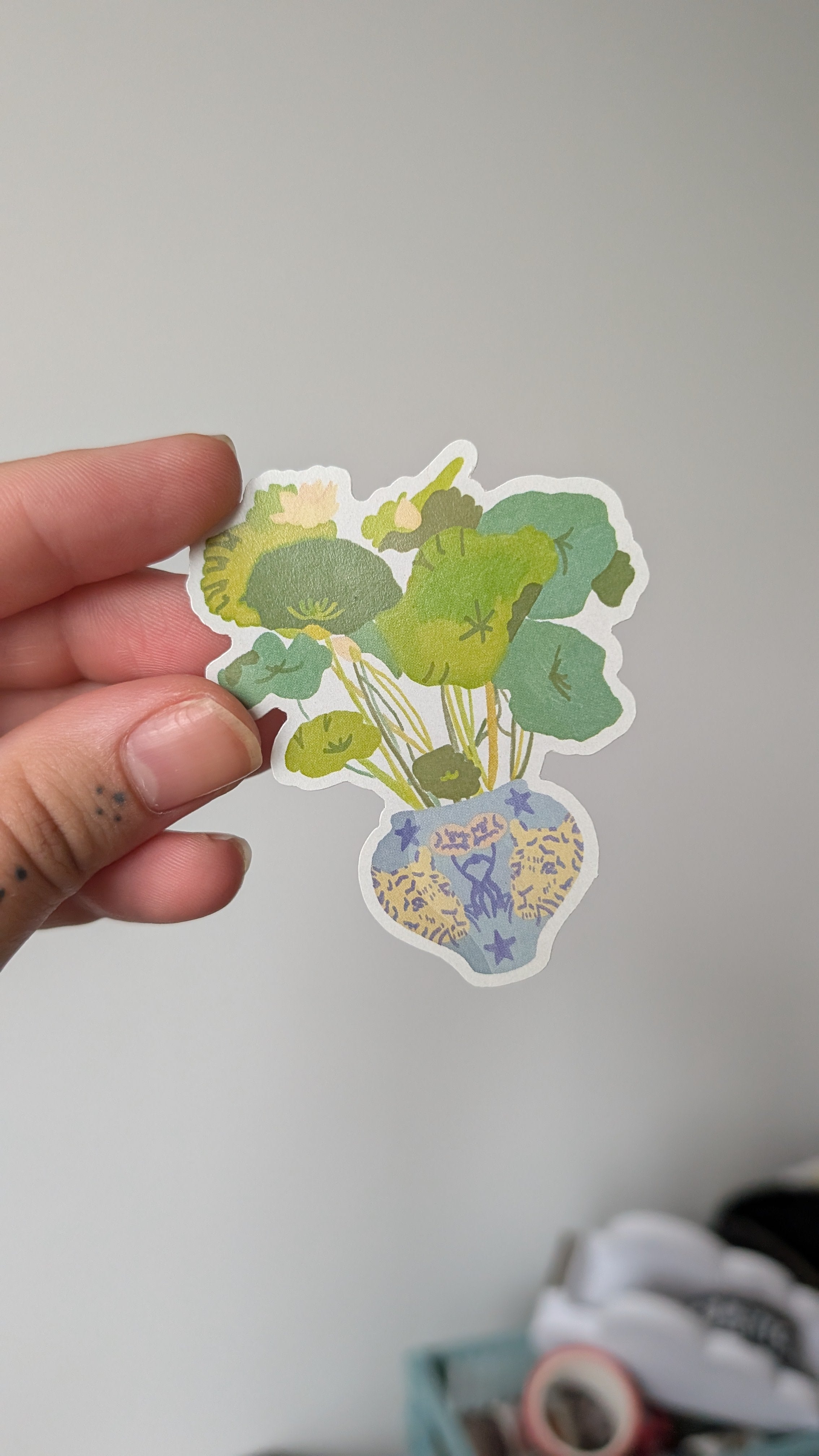 Sticker of a lotus flower in a vase. The vase is pale blue with a tiger design.