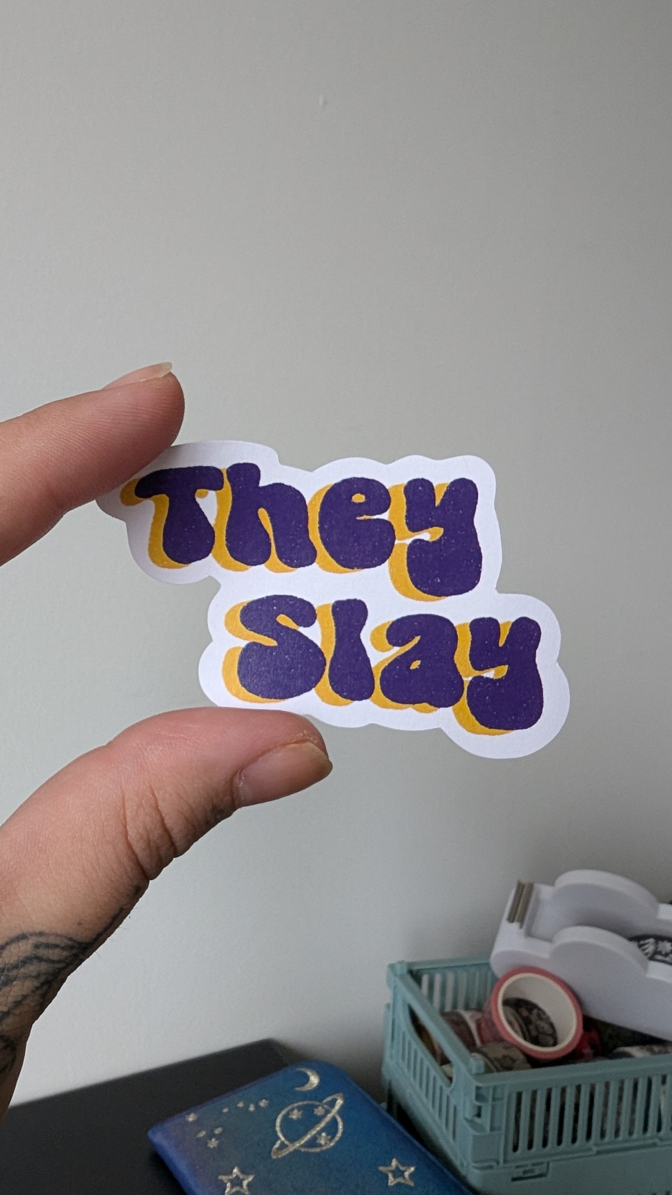 Sticker of an infinity symbol featuring the colours purple and yellow (some of the colours of the non binary pride flag).