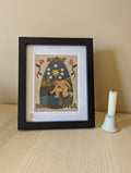 Art print of a figure filling a vessel of water. The piece is based on The Star tarot deck. The figure is nude, chubby, transgender person. The print is photographed in a black frame. A candle sits beside the frame.